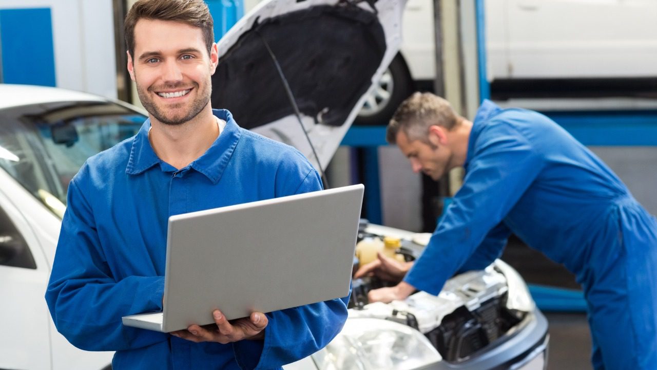 Smiling Mechanic Using A Laptop